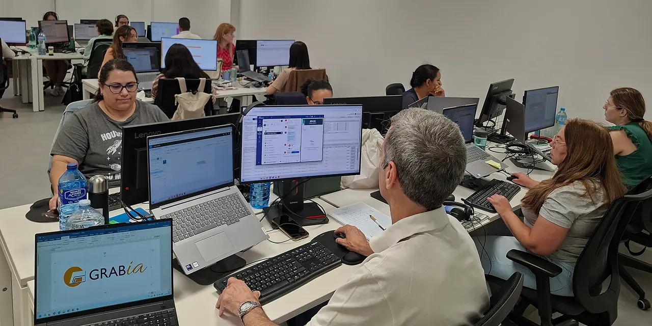 Fotografía de las oficinas de Grabía, con varias personas del equipo trabajando con ordenadores en sus puestos de trabajo